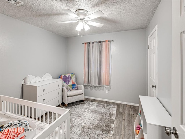 1810 Haynie Ln, Prague, OK 74864 - bedroom featuring a crib, wood finished floors, a textured ceiling, a ceiling fan, and baseboards