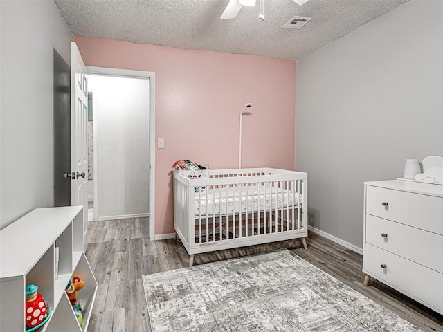 1810 Haynie Ln, Prague, OK 74864 - bedroom with wood finished floors, a crib, a textured ceiling, and ceiling fan