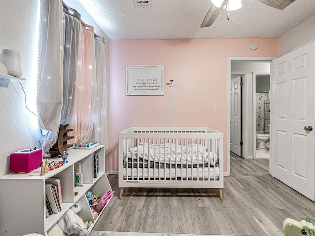 1810 Haynie Ln, Prague, OK 74864 - bedroom with wood finished floors, a textured ceiling, a nursery area, and ceiling fan