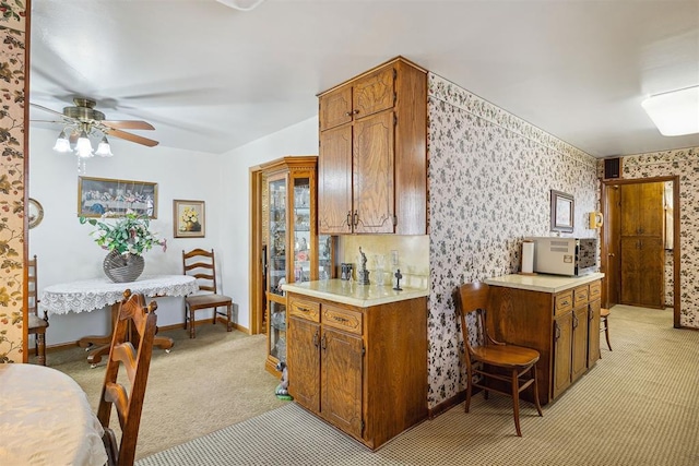 111 W Colorado Ave, Okarche, OK 73762 - kitchen with light carpet, wallpapered walls, light countertops, ceiling fan, and brown cabinets