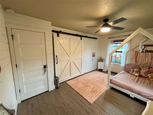 11790 E Etowah Rd, Noble, OK 73068 - bedroom with a barn door, dark wood finished floors, a textured ceiling, and a ceiling fan
