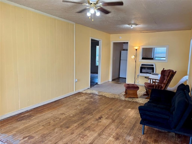 703 W B Ave, Elk City, OK 73644 - living room featuring heating unit, hardwood / wood-style flooring, ceiling fan, a textured ceiling, and baseboards