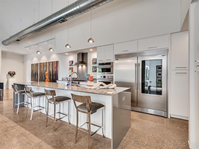 15929 Aparados Way, Edmond, OK 73013 - kitchen featuring stainless steel appliances, a sink, wall chimney range hood, modern cabinets, and a kitchen breakfast bar