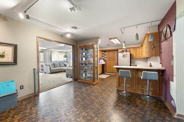 5712 NW 34th St, Oklahoma City, OK 73122 - kitchen with track lighting, freestanding refrigerator, baseboards, a textured ceiling, and a peninsula