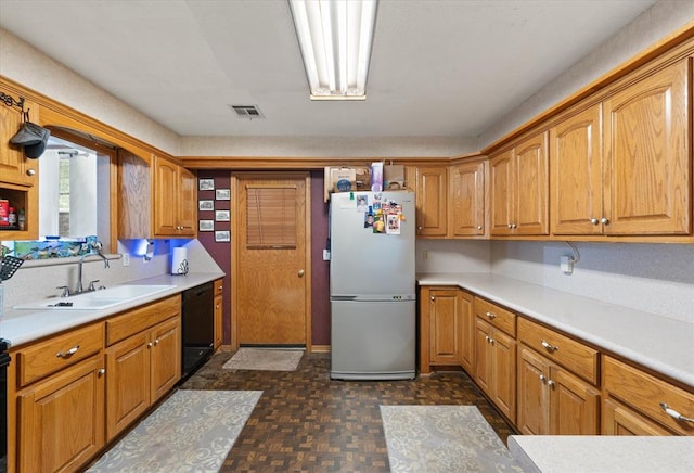 5712 NW 34th St, Oklahoma City, OK 73122 - kitchen with freestanding refrigerator, a sink, black dishwasher, light countertops, and brown cabinets