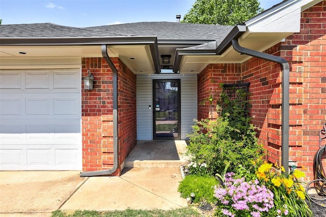 1001 Glacier Ln, Edmond, OK 73003 - view of exterior entry with an attached garage, brick siding, and a shingled roof