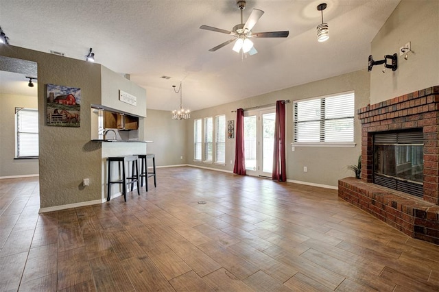 1001 Glacier Ln, Edmond, OK 73003 - living room featuring a fireplace, vaulted ceiling, a ceiling fan, dark wood finished floors, and a chandelier