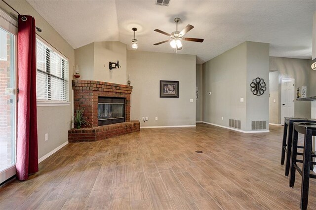 1001 Glacier Ln, Edmond, OK 73003 - unfurnished living room with ceiling fan, wood finished floors, a brick fireplace, baseboards, and vaulted ceiling