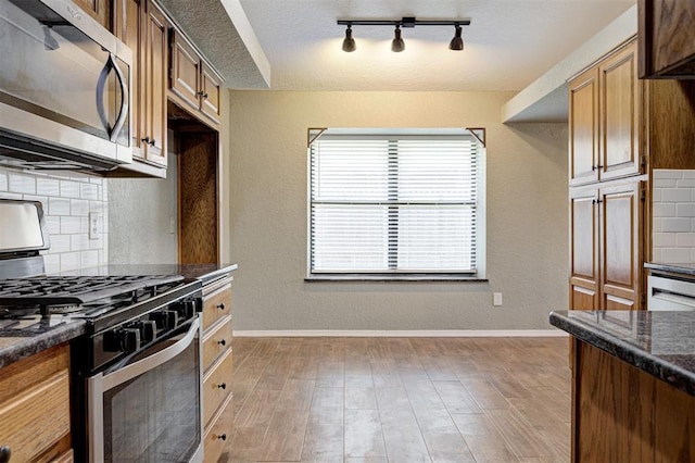 1001 Glacier Ln, Edmond, OK 73003 - kitchen with appliances with stainless steel finishes, backsplash, baseboards, rail lighting, and a textured ceiling