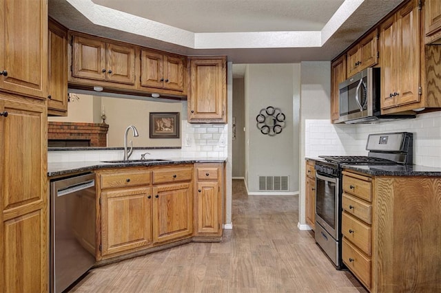 1001 Glacier Ln, Edmond, OK 73003 - kitchen with appliances with stainless steel finishes, a sink, backsplash, brown cabinetry, and light wood-type flooring