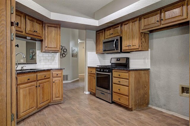 1001 Glacier Ln, Edmond, OK 73003 - kitchen with appliances with stainless steel finishes, a sink, light wood finished floors, backsplash, and baseboards