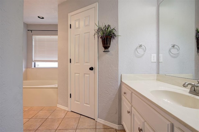 1001 Glacier Ln, Edmond, OK 73003 - full bath featuring a textured wall, vanity, a garden tub, tile patterned floors, and baseboards