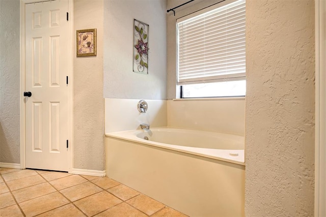 1001 Glacier Ln, Edmond, OK 73003 - bathroom with a textured wall, a garden tub, tile patterned flooring, and baseboards