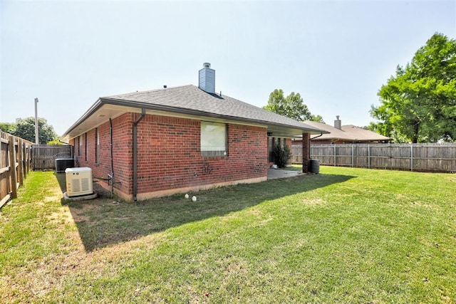 1001 Glacier Ln, Edmond, OK 73003 - rear view of house featuring central AC unit, brick siding, a chimney, and roof with shingles