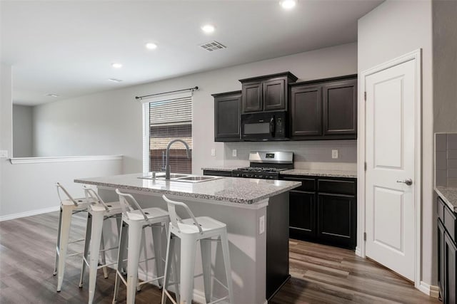 11325 SW 34th Ter, Yukon, OK 73099 - kitchen featuring stainless steel range with gas stovetop, black microwave, a sink, a center island with sink, and dark wood finished floors