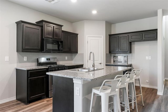 11325 SW 34th Ter, Yukon, OK 73099 - kitchen with black microwave, a sink, stainless steel range with gas cooktop, backsplash, and a kitchen island with sink