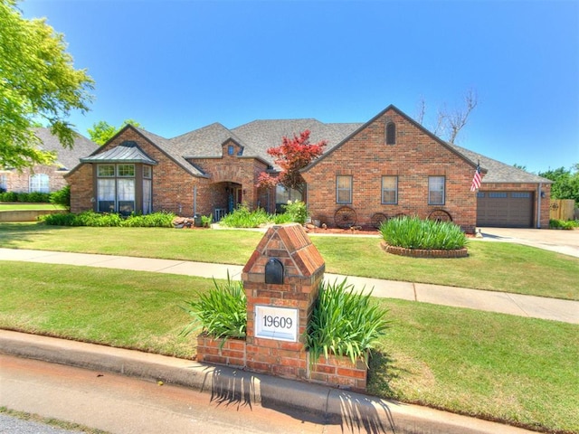 19609 Filly Dr, Edmond, OK 73003 - tudor house featuring a front yard, an attached garage, driveway, and brick siding