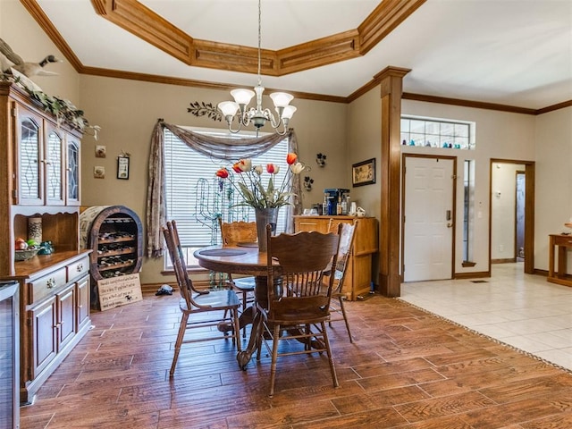 19609 Filly Dr, Edmond, OK 73003 - dining room featuring a chandelier, a tray ceiling, wood finished floors, ornamental molding, and baseboards
