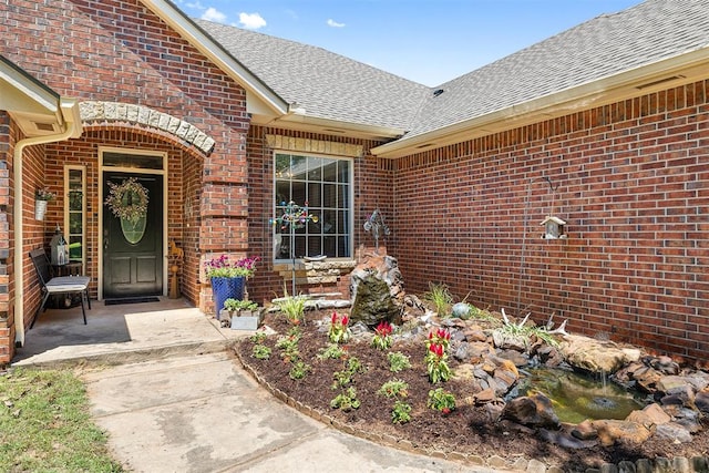 4706 Red Hawk St, Guthrie, OK 73044 - entrance to property featuring roof with shingles, brick siding, and a small pond