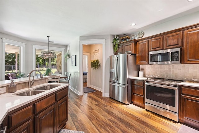 4706 Red Hawk St, Guthrie, OK 73044 - kitchen featuring stainless steel appliances, a sink, light countertops, tasteful backsplash, and wood finished floors