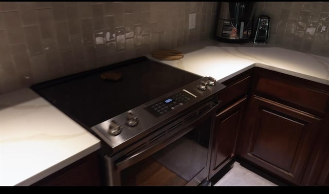 4706 Red Hawk St, Guthrie, OK 73044 - kitchen featuring stainless steel range with electric stovetop, backsplash, light countertops, and dark brown cabinetry