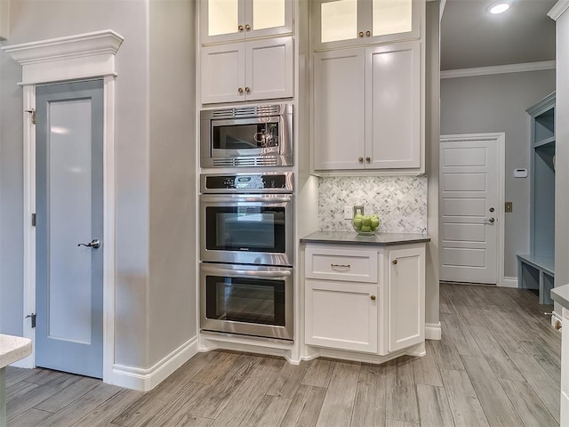 12801 Red Spruce Cir, Oklahoma City, OK 73142 - kitchen with stainless steel appliances, crown molding, baseboards, white cabinetry, and light wood-style floors