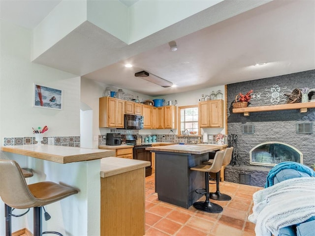 43 W Shore Dr, Arcadia, OK 73007 - kitchen featuring black appliances, a breakfast bar, a peninsula, light brown cabinets, and recessed lighting