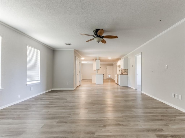 18 Whispering Meadows Rd, Shawnee, OK 74804 - unfurnished living room featuring ceiling fan, ornamental molding, a textured ceiling, light wood-style floors, and baseboards