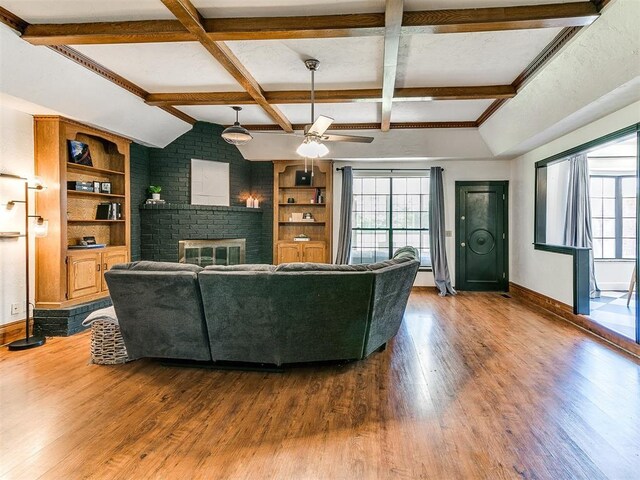 4205 Sooner Cir, Edmond, OK 73034 - living room featuring baseboards, wood finished floors, beam ceiling, a ceiling fan, and a brick fireplace
