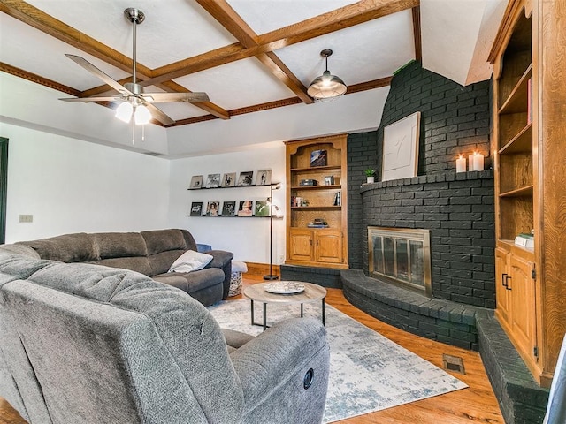 4205 Sooner Cir, Edmond, OK 73034 - living room featuring wood finished floors, a ceiling fan, beamed ceiling, a brick fireplace, and coffered ceiling