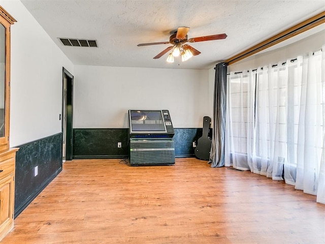 4205 Sooner Cir, Edmond, OK 73034 - sitting room with a ceiling fan, light wood-style flooring, a textured ceiling, and a wainscoted wall