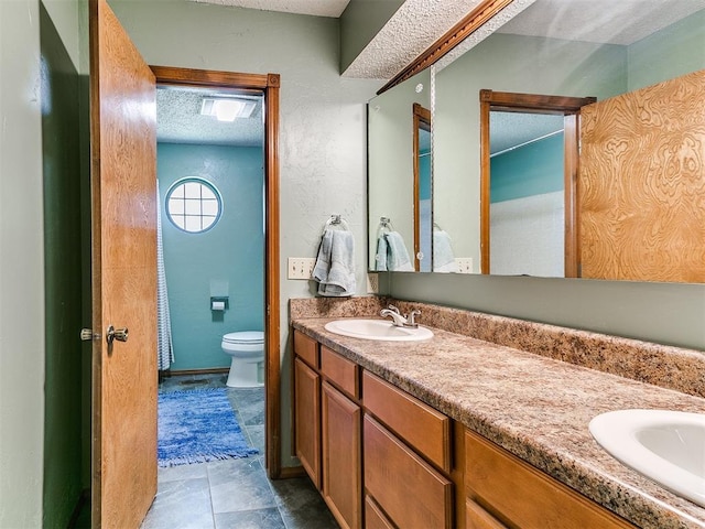 4205 Sooner Cir, Edmond, OK 73034 - bathroom featuring double vanity, toilet, and a textured ceiling