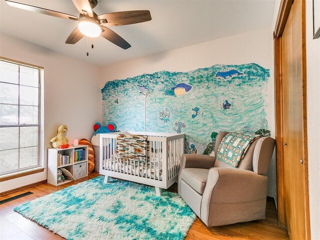 4205 Sooner Cir, Edmond, OK 73034 - bedroom featuring wood finished floors, a nursery area, ceiling fan, and baseboards