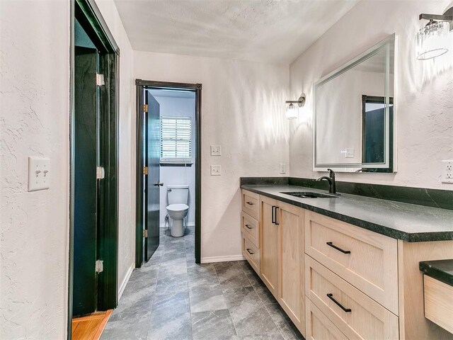 4205 Sooner Cir, Edmond, OK 73034 - bathroom with vanity, toilet, a textured wall, and baseboards