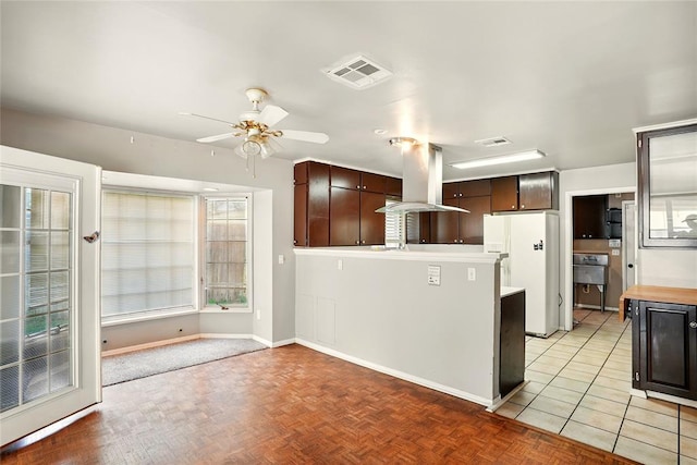 6005 NW Kingston Rd, Oklahoma City, OK 73122 - kitchen with island exhaust hood, freestanding refrigerator, ceiling fan, baseboards, and dark brown cabinets