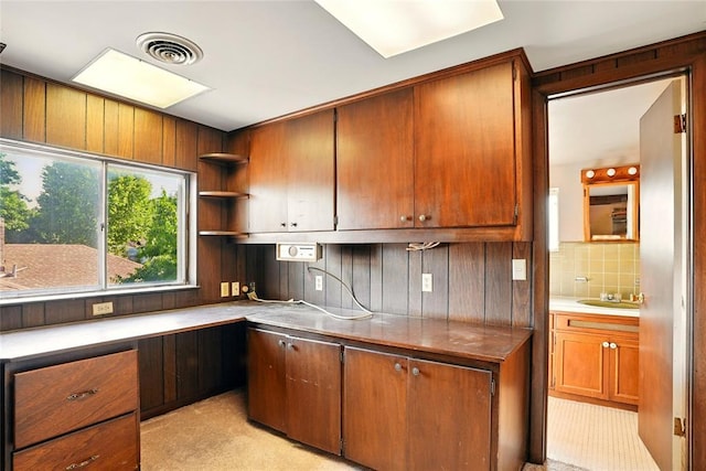 6005 NW Kingston Rd, Oklahoma City, OK 73122 - kitchen featuring open shelves, brown cabinetry, tasteful backsplash, wooden walls, and a sink