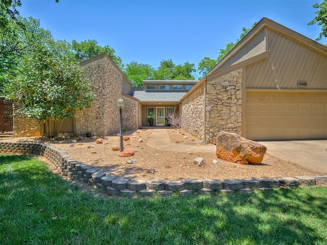 5101 Long Branch Ln, Edmond, OK 73034 - mid-century modern home with stone siding, an attached garage, and driveway