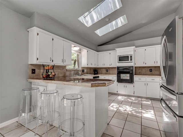 5101 Long Branch Ln, Edmond, OK 73034 - kitchen featuring stainless steel appliances, a peninsula, vaulted ceiling, backsplash, and white cabinets