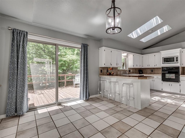 5101 Long Branch Ln, Edmond, OK 73034 - kitchen with oven, stainless steel microwave, a peninsula, a skylight, and vaulted ceiling