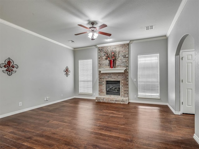 4033 NE 138th St, Edmond, OK 73013 - unfurnished living room featuring a ceiling fan, wood finished floors, a fireplace, arched walkways, and crown molding