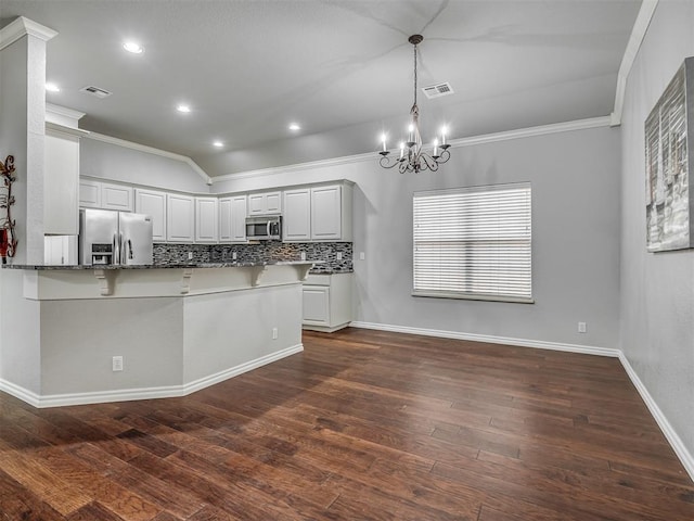 4033 NE 138th St, Edmond, OK 73013 - kitchen with appliances with stainless steel finishes, crown molding, a kitchen breakfast bar, a chandelier, and dark stone countertops