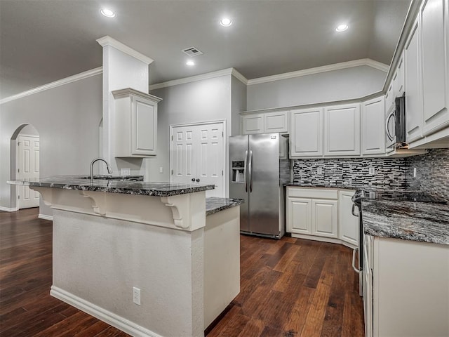 4033 NE 138th St, Edmond, OK 73013 - kitchen with appliances with stainless steel finishes, crown molding, a peninsula, a breakfast bar area, and dark stone counters