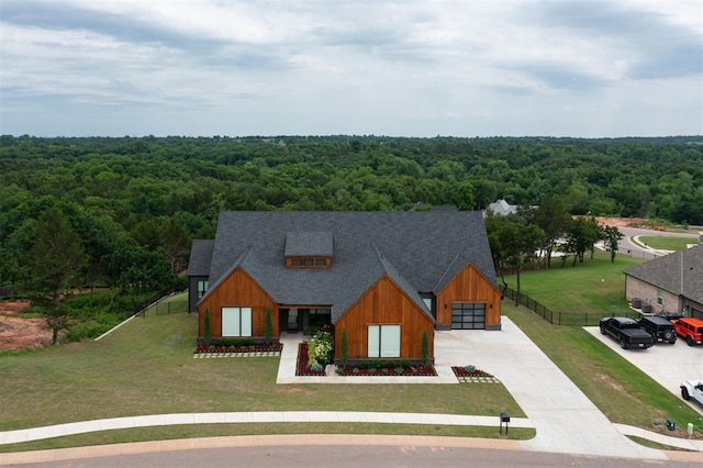 6508 NE 96th Cir, Oklahoma City, OK 73151 - view of front of home with a forest view, concrete driveway, board and batten siding, and a shingled roof
