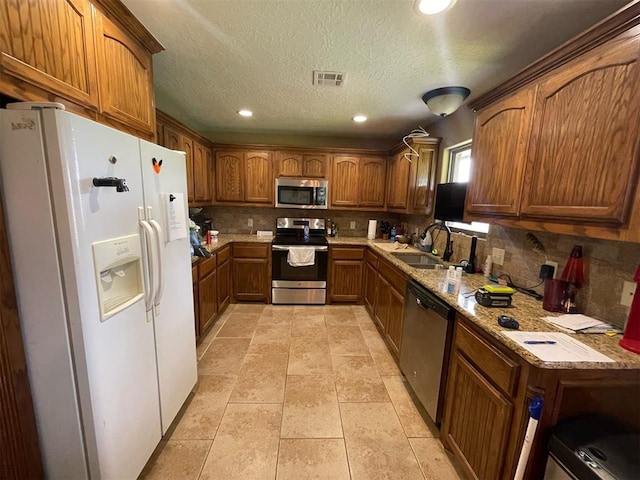 103 Thurman Dr, Walters, OK 73572 - kitchen with appliances with stainless steel finishes, a sink, brown cabinets, backsplash, and recessed lighting