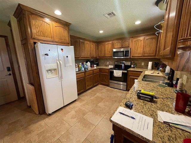 103 Thurman Dr, Walters, OK 73572 - kitchen featuring stainless steel appliances, brown cabinetry, a sink, decorative backsplash, and recessed lighting