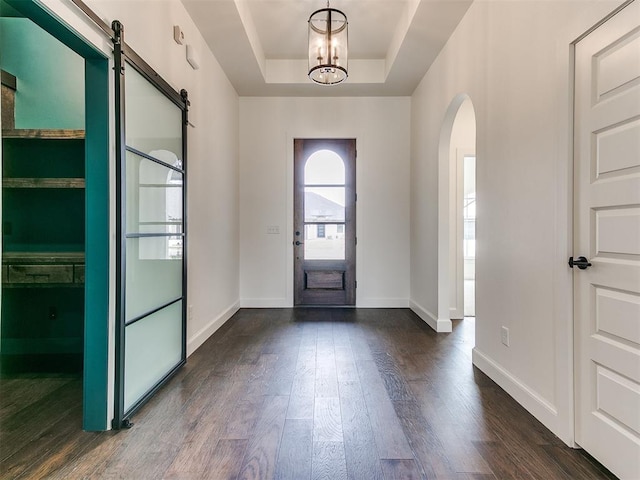 9316 NW 84th St, Yukon, OK 73099 - entryway featuring arched walkways, dark wood-style flooring, a barn door, a chandelier, and a tray ceiling