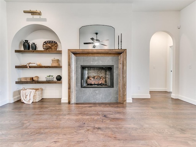 9316 NW 84th St, Yukon, OK 73099 - living area with arched walkways, ceiling fan, wood finished floors, a fireplace, and baseboards