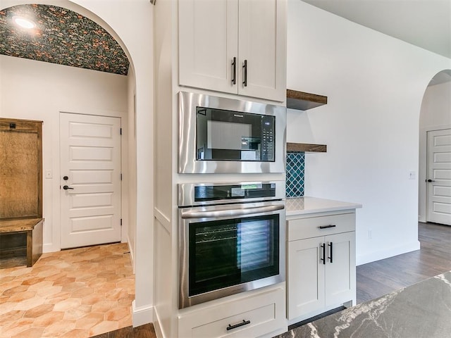 9316 NW 84th St, Yukon, OK 73099 - kitchen with stainless steel oven, built in microwave, arched walkways, tasteful backsplash, and baseboards