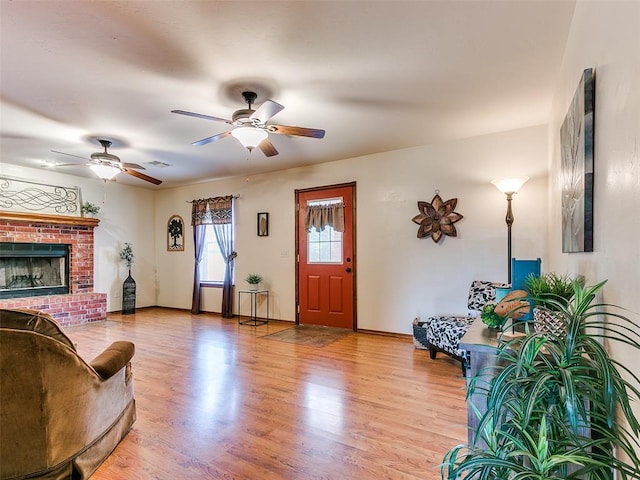 409 NW Jefferson Ave, Piedmont, OK 73078 - living room featuring a ceiling fan, light wood-style flooring, a brick fireplace, and baseboards