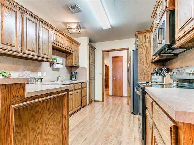 409 NW Jefferson Ave, Piedmont, OK 73078 - kitchen featuring appliances with stainless steel finishes, light countertops, light wood finished floors, and backsplash